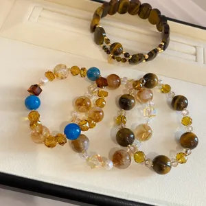 Primer plano detallado de pulseras de cuentas de piedras preciosas con ojo de tigre y cristales.