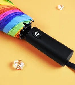 Nahaufnahme des automatischen Regenbogen-Faltschirmgriffs und des bunten regendichten Stoffes.