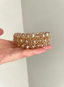 Primer plano detallado de una pulsera de cadena dorada con cuentas facetadas brillantes.