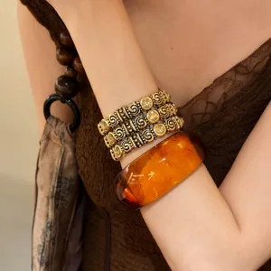 Vintage-stil elastisches Goldarmband und Bernsteinfarbenes Resin-Armband, Schmuckdetail.