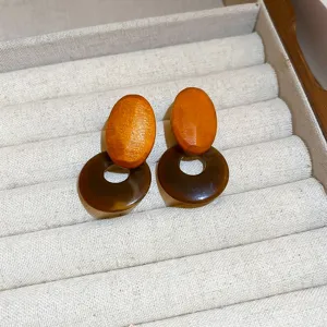 Nahaufnahme von bohemischen Holz und dunkelbraunen Harz geometrischen Ohrringen auf beige Schmuck