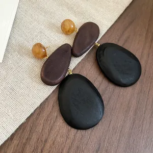 Nahaufnahme Detailansicht von bohemian Holz-Ohrringen mit Naturharzperlen und schwarzen Anhängern.