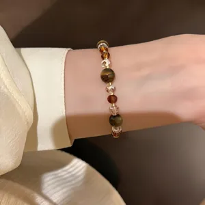 Close-up detail shot of the retro brown crystal tiger eye beaded bracelet on the wrist.