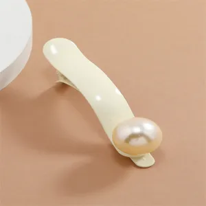 Closeup of elegant metal hair duckbill clip decorated with a large glossy white pearl detail.
