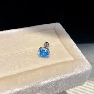Detailed close-up of a vibrant blue zircon round stud earring on a soft beige velvet tray.