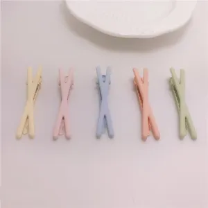 Colorful X shaped hair clips detail view, cute matte finish hair styling pins for kids daily wear.