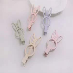 Close-up detail of cute pastel bunny ear hair clips, colorful rubber paint surface accessories
