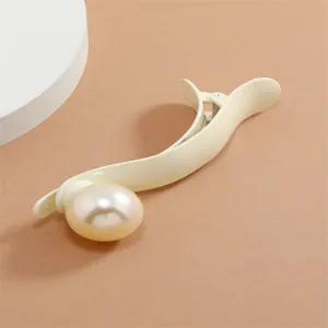 Close-up detail of a chic matte beige hair claw clip featuring a large elegant faux pearl decoration.