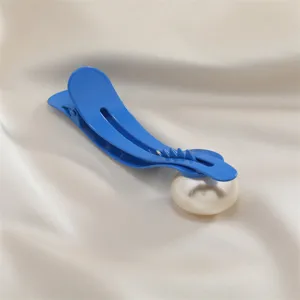 Detailed close-up of a stylish blue duckbill hair clip featuring a large faux pearl decoration.