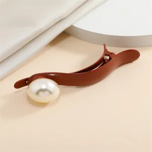 Detail shot of elegant brown hair claw clip with large faux pearl, stylish daily hair accessory.