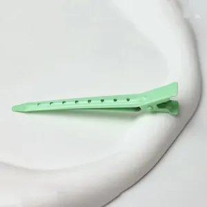 Green hair duckbill clip for salon styling and sectioning, durable metal detailed shot.