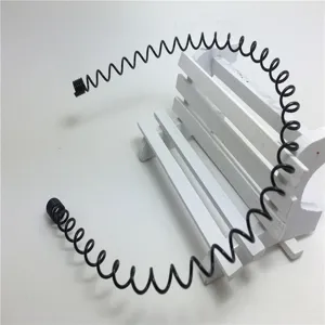 Detailansicht eines schwarzen Spiral-Feder-Haarbandes auf einer weissen Holzsitzbank.