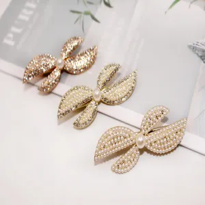 Detailed close-up shot of elegant bow-shaped pearl and rhinestone hair clips on clean background.