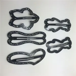 Vista dettagliata di fermagli per capelli in metallo nero con forme geometriche traforate uniche.