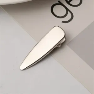 Silver metal duckbill hair clip detail shot, minimalist side hair accessory close-up view.