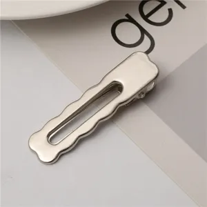 Close-up of a stylish silver metallic hair clip with a hollow wavy design for chic styling.