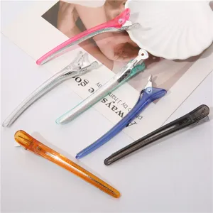 Primo piano di mollette per capelli trasparenti da 12cm in plastica per acconciature professionali.