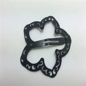 Primo piano di un fermaglio per capelli in metallo nero con design intagliato irregolare unico.