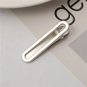 Detailed shot of a sleek silver metal hair clip, minimalist duckbill design, close-up view.