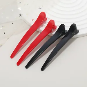 Detail shot of hairdressing sectioning duckbill clips in red and black colors for salon use.
