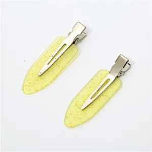 Detail view of sparkly yellow hair clips, glitter duckbill clips for makeup and bangs styling.