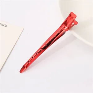 Red metal sectioning hair clip detail, professional styling accessory with hollow design for salon.