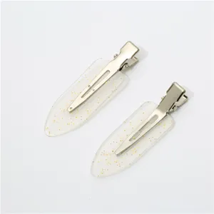 Close-up detail of transparent resin hair clips with gold glitter and metal duckbill clasp.