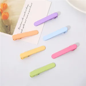 Close-up detail shot of colorful candy-toned duckbill hair clips neatly arranged on a clean white surface.
