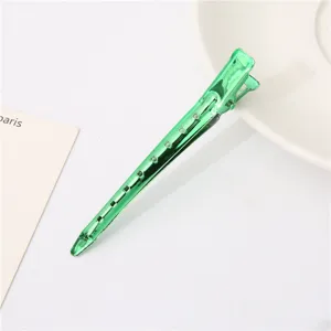 Green metallic duckbill hair clip with cutout design for hair styling and sectioning.