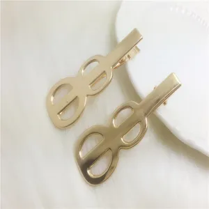 Gold metal duckbill hair clip detail shot, hollow geometric design, shiny hair accessory.