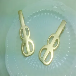Gold guitar shaped hair clips close up, stylish metal duckbill clips for daily hair styling.
