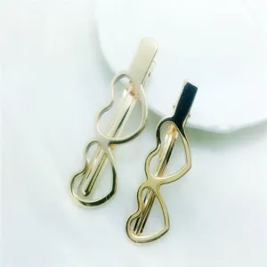 Close up detail of stylish gold hollow heart metal hair clips, elegant duckbill clip design.