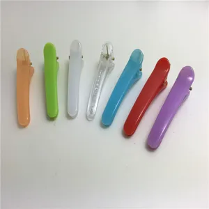 Detailed view of colorful mini plastic duckbill hair clips, assorted bright shades.