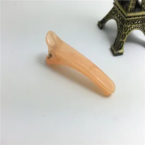 Detail view of a 5cm translucent peach plastic duckbill hair clip, mini styling pin accessory.