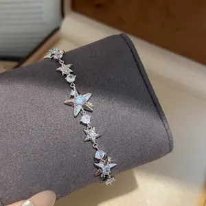 Primer plano detallado de una delicada pulsera plateada con dijes de estrellas.