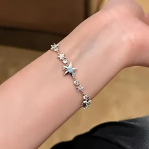 Primer plano detallado de la delicada pulsera de plata con estrellas brillantes en la muñeca.