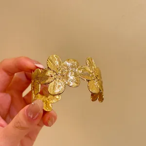 Vue détail bracelet manchette fleur dorée, bijoux design floral vintage en métal.