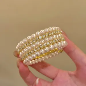 Vue détaillée d'un bracelet manchette doré multicouche orné de perles et de strass étincelants.