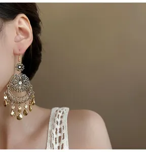 Close-up detail of vintage ethnic style gold filigree flower and waterdrop tassel earrings.