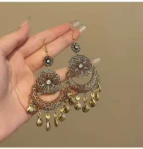 Close-up detail of vintage ethnic style gold filigree flower teardrop tassel earrings.
