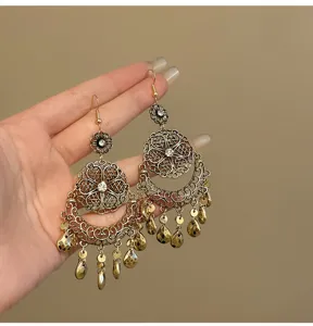 Vintage filigree teardrop dangle earrings detail shot, ornate metal cutout drop charms.