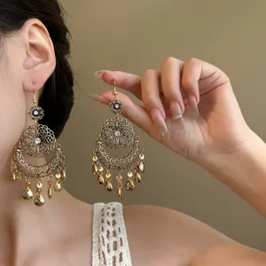 Vintage gold dangle earrings detail, intricate flower motif and shimmering rhinestone drops.