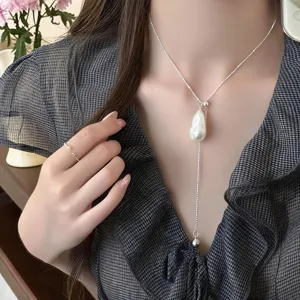 Primo piano dettagliato di una delicata collana in argento a Y con perla barocca.