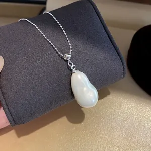Primo piano dettaglio della collana con ciondolo di perla barocca, catena fine, stile.