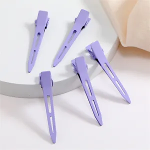 Detail view of five purple metal duckbill hair clips with matte finish for styling and sectioning.