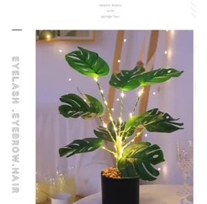 Detalle en primer plano de la lámpara planta monstera artificial con luces LED cálidas.