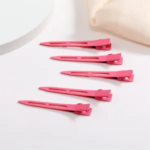 Detail view of pink metal duckbill hair clips, matte finish, neat arrangement for styling.
