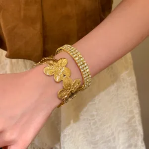 Vue détaillée du bracelet en métal doré motif fleur associé à un superbe bracelet en strass.