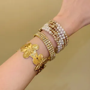 Manchette florale dorée vintage et ensemble de bracelets empilés en perles de strass multicouches.