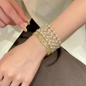 Vue détaillée de bracelets dorés à perles et strass superposés pour un style élégant.